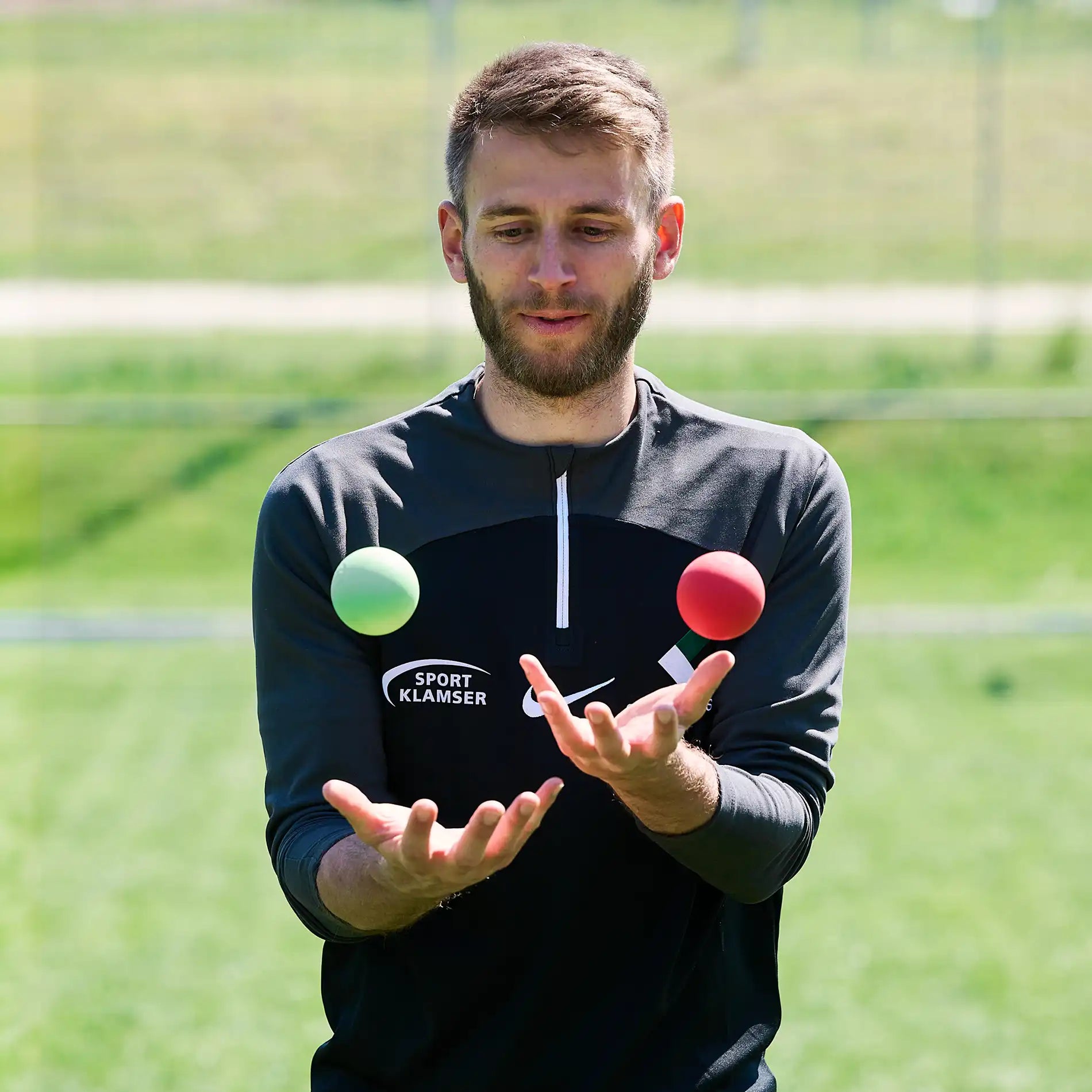 ARTZT neuro BrainBoost Ball – Reaktionsball für Neuroathletik im Fußball: Simon Jans jongliert grünen und roten Ball vor der Brust auf dem Platz