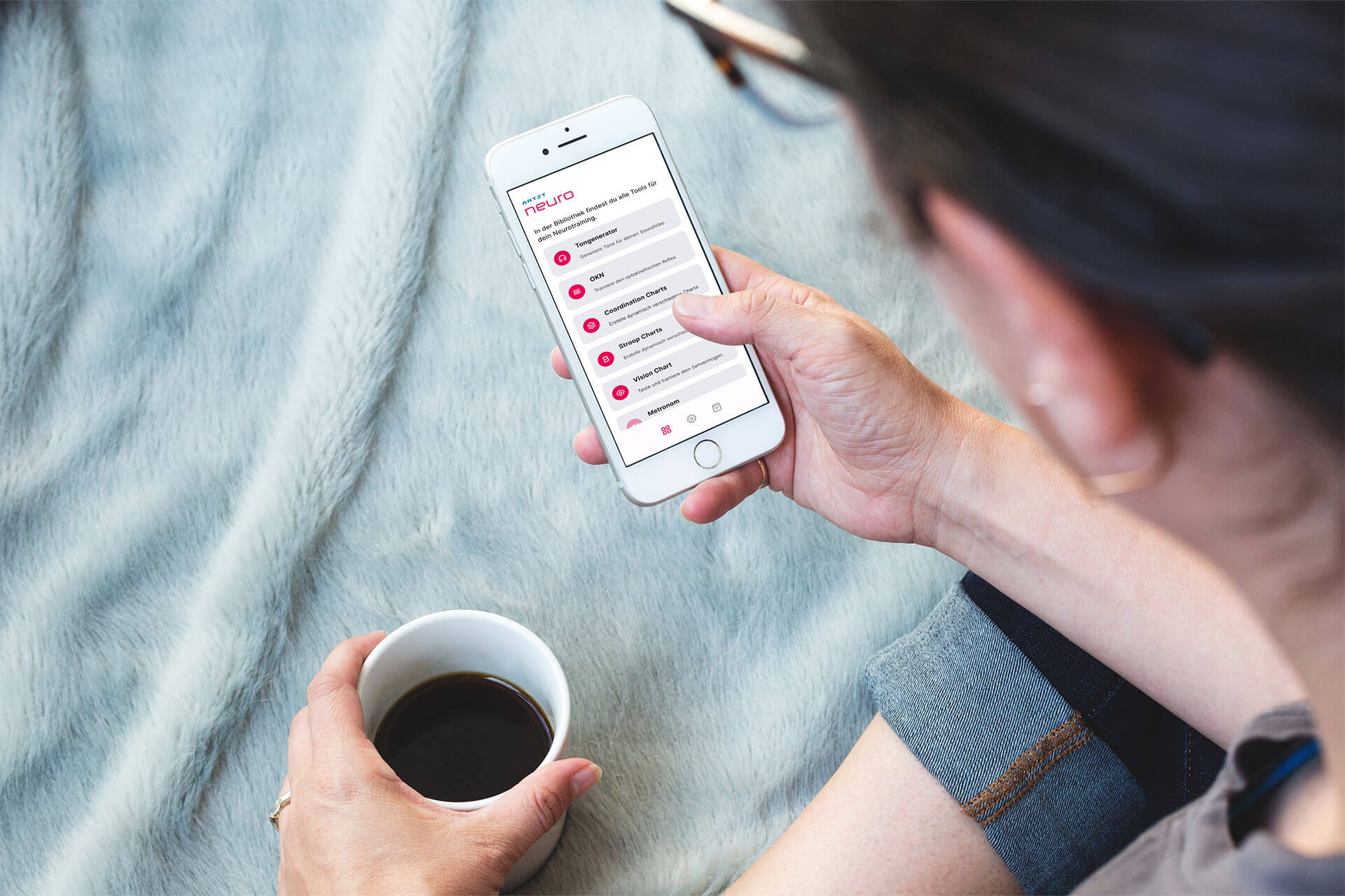 Frau sitzt im Schneidersitz auf dem Bett und hat auf ihrem Smartphone die Neuroathletik App neurally geöffnet.