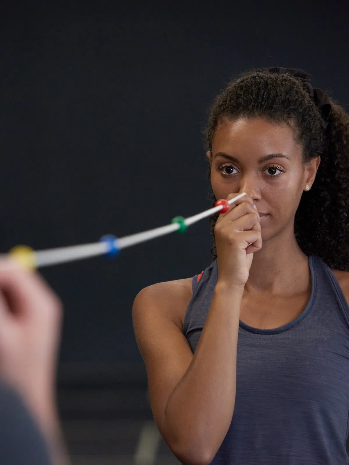 Frau hält sich das professionelle Neuroathletik Tool Brock String an die Nasenspitze | Mobile Image