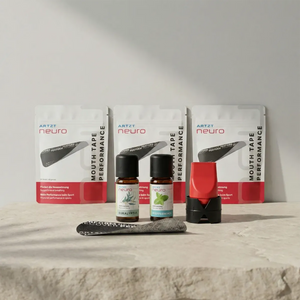 Produktaufnahme des ARTZT neuro Performance Breathing Set mit drei Packungen Mouth Tape Performance, zwei ätherischen Ölen (Eukalyptus und Pfefferminze), einem roten Atemtrainer mit schwarzem Standfuß sowie einem einzelnen Mouth Tape auf einer hellen Steinplatte vor neutralem Hintergrund. SET 1019 #mengenrabatt_3 monate