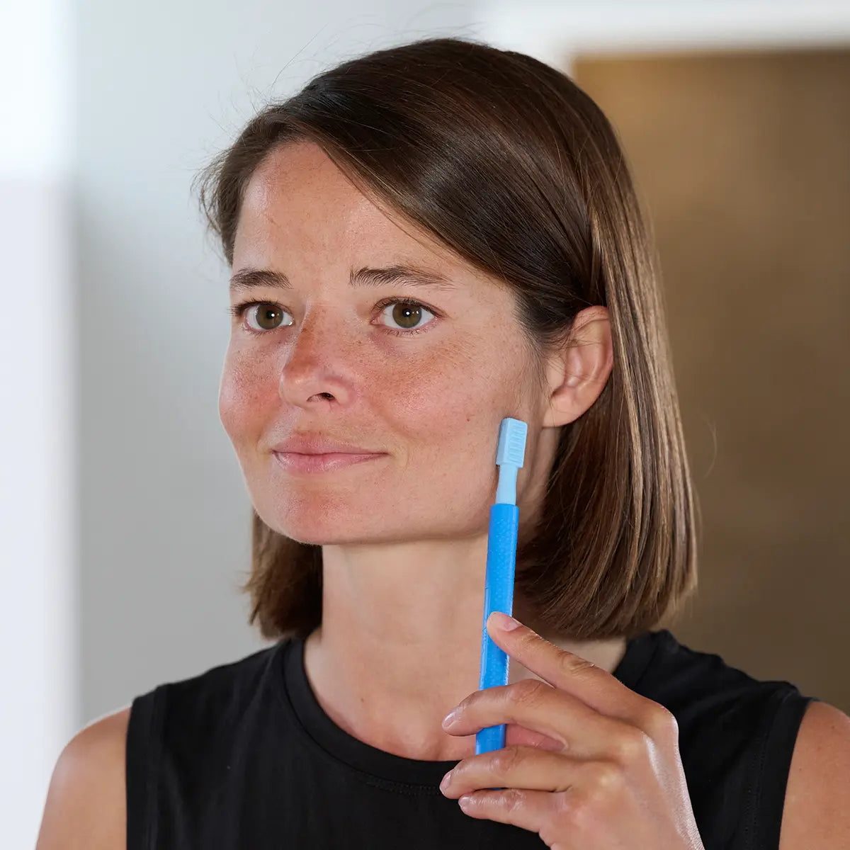 Frau hält sich einen Z-Vibe Vibrationsstift an die linke Wange