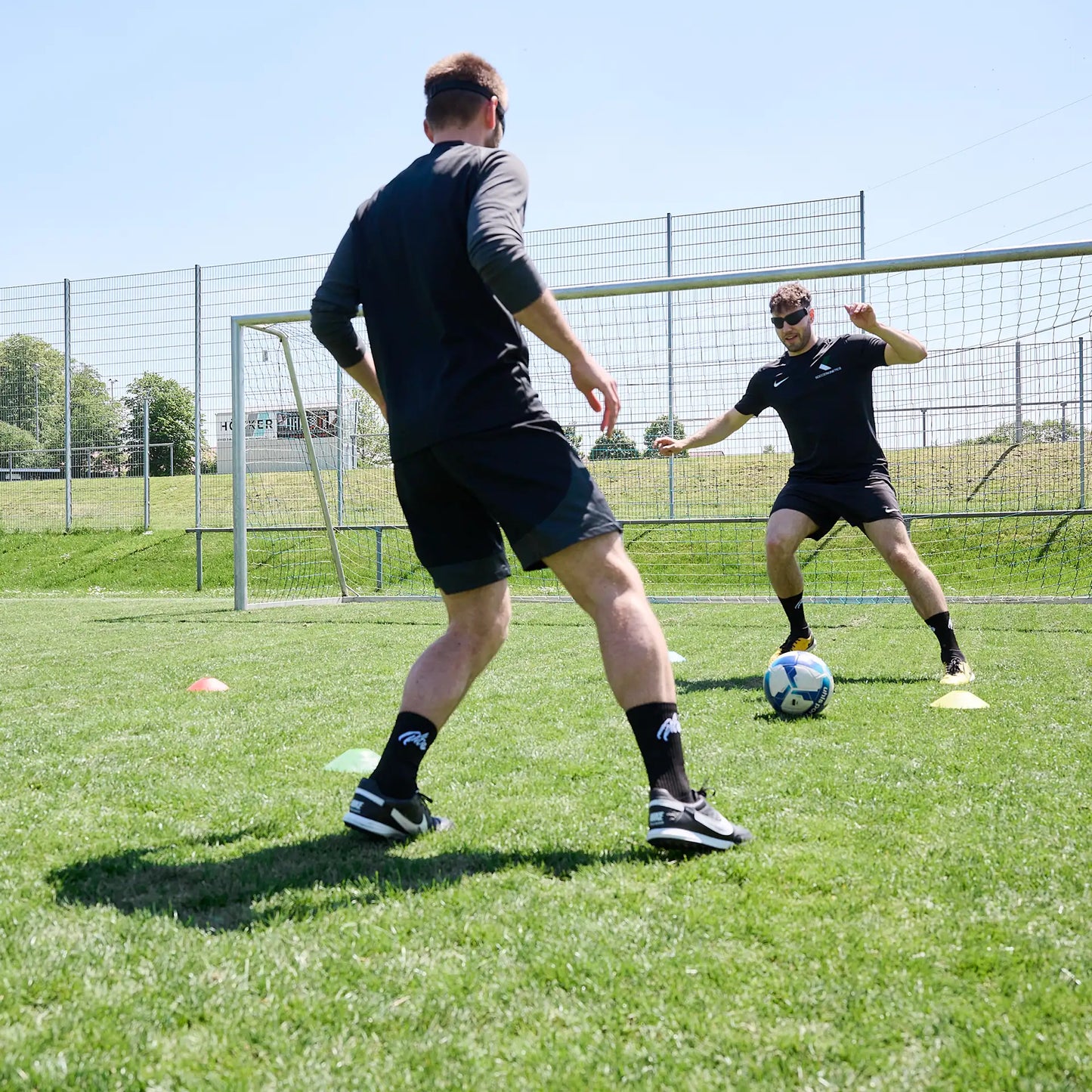 Zwei Fußballer beim neurozentrierten Fußballtraining mit einer Rasterbrille aus dem ARTZT neuro Fußball Set.