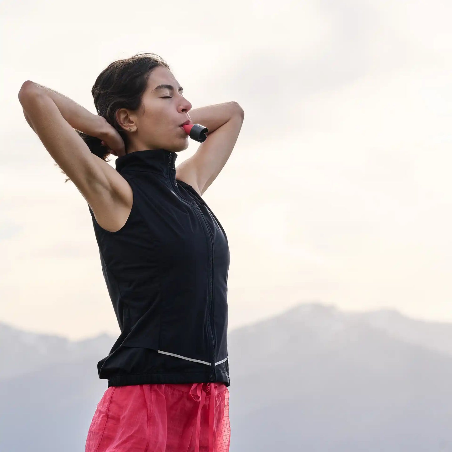 Frau in den Alpen atmet tief ein mit dem ARTZT Neuro Atemtrainer