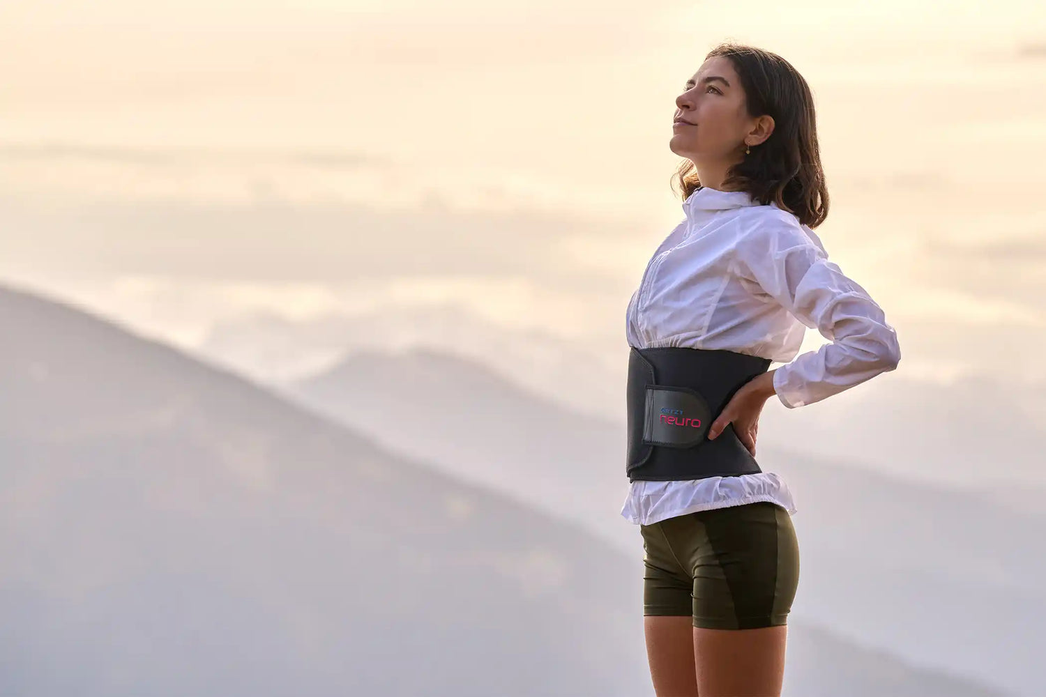 Frau steht vor einem Bergpanorama und trägt den ARTZT neuro Atemtrainer.