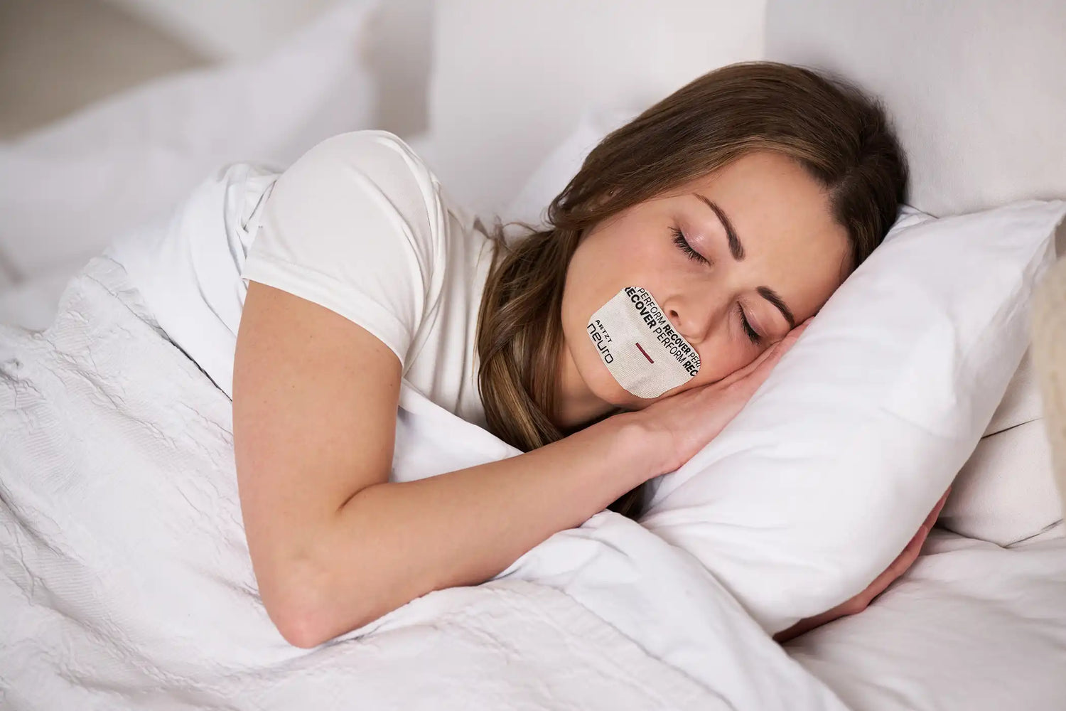 Frau liegt schlafend im Bett und trägt ein ARTZT neuro Mouth Tape Recovery auf dem Mund.