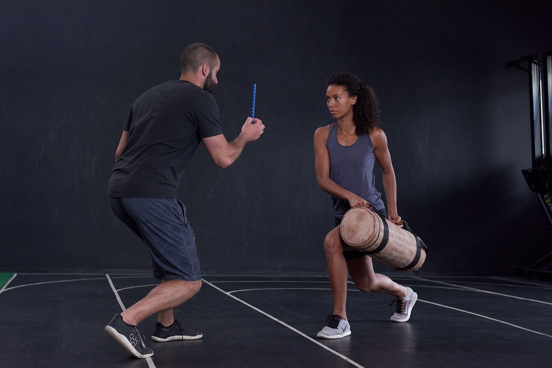 Mann hält einen ARTZT neuro Vision Stick, eine Frau richtet ihren Blick darauf, während sie mit einer Fitnessbag trainiert.