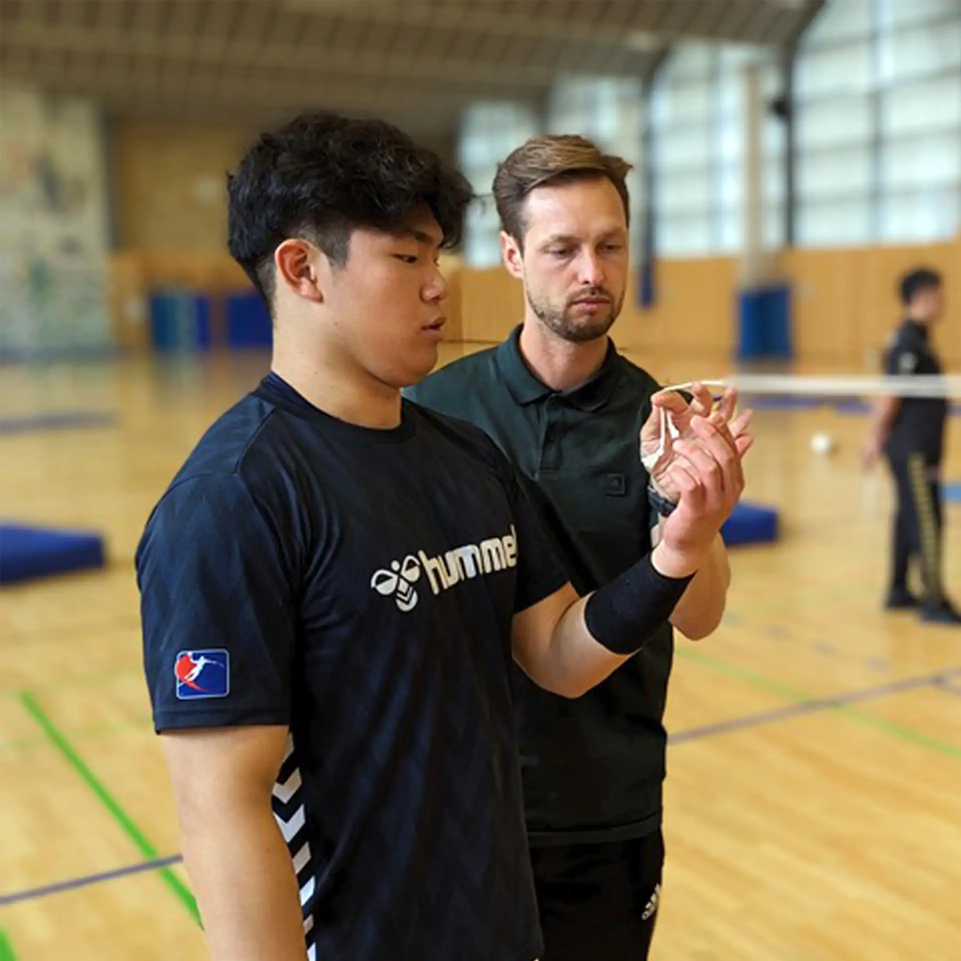 Zwei Männer stehen in einer Turnhalle und halten eine Brock Schnur mit jeweils einer Hand.