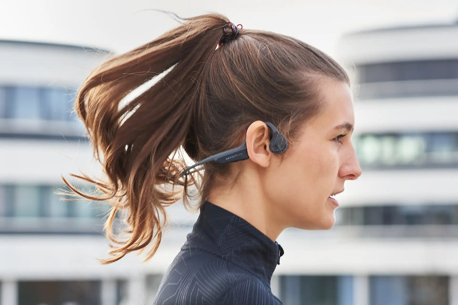 Kopf einer Frau im Profil, die den ARTZT neuro Soundvibe Knochenschall Kopfhörer trägt.