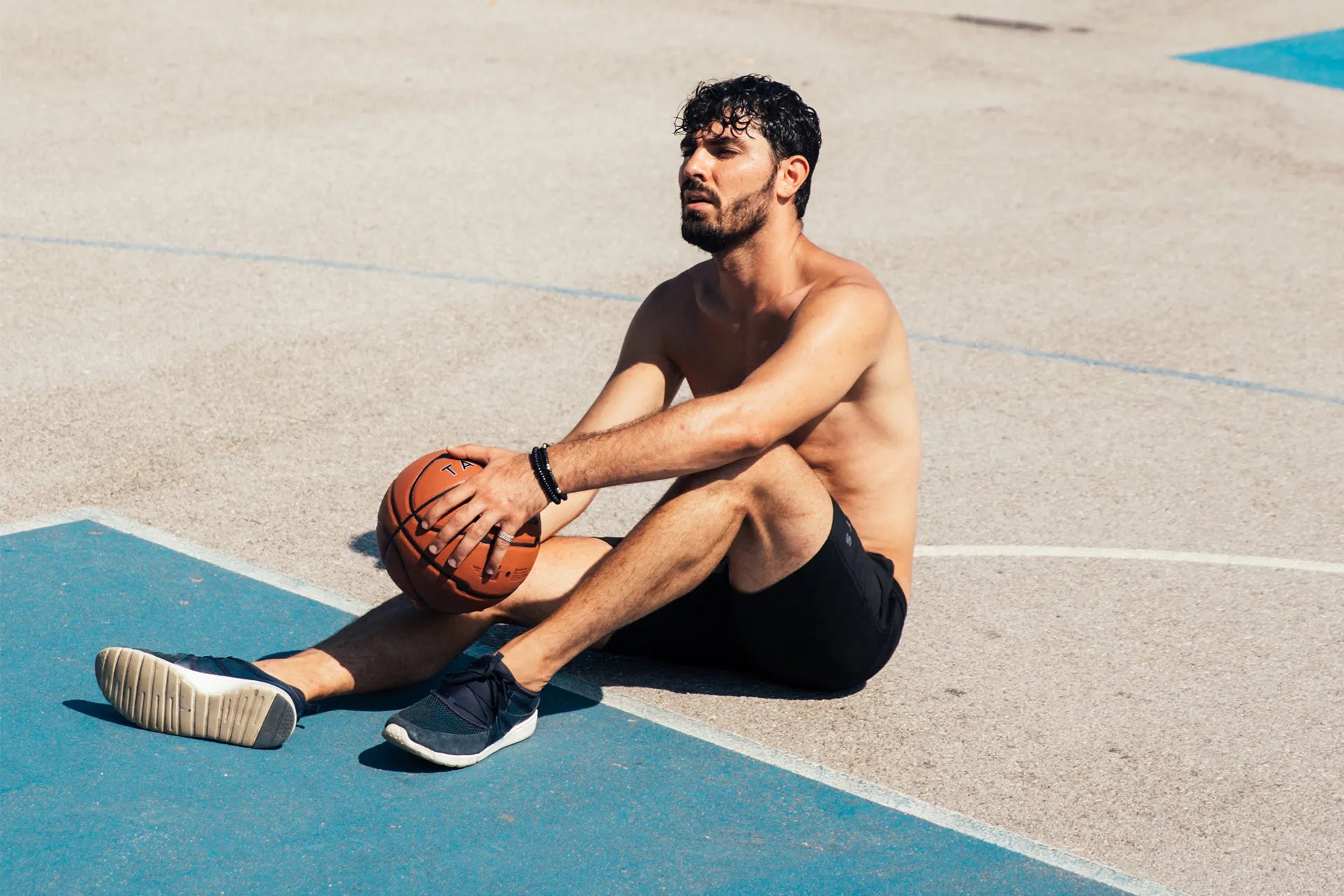 Mann sitzt mit erschöpftem Gesicht auf dem Boden mit einem Basketball in der Hand | ARTZT neuro Mouth Tape Performance